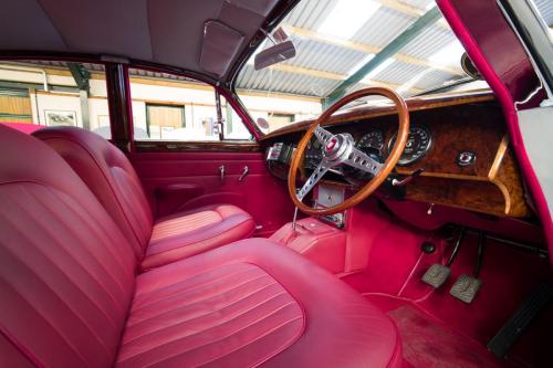 Photograph of the interior of a classic Jaguar, with red leather seats and trim.